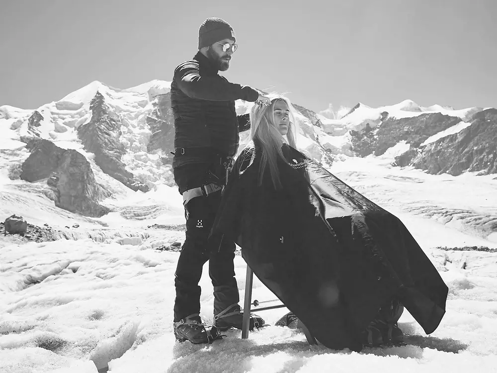 Friseur schneidet auf einem Berg die Haare.