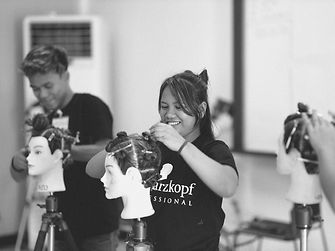 eine Frau übt an einem Puppenkopf eine Frisur