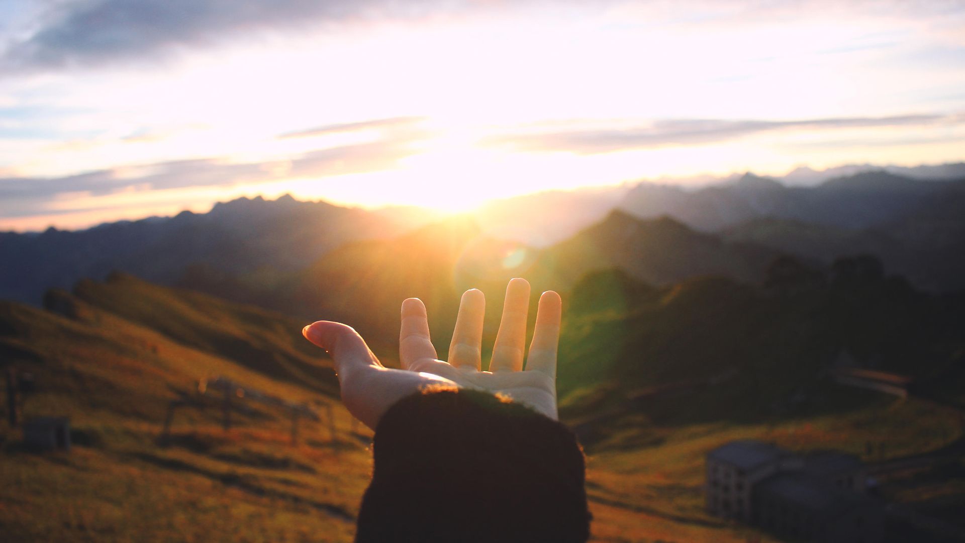 Hand reaching out towards the sunrise
