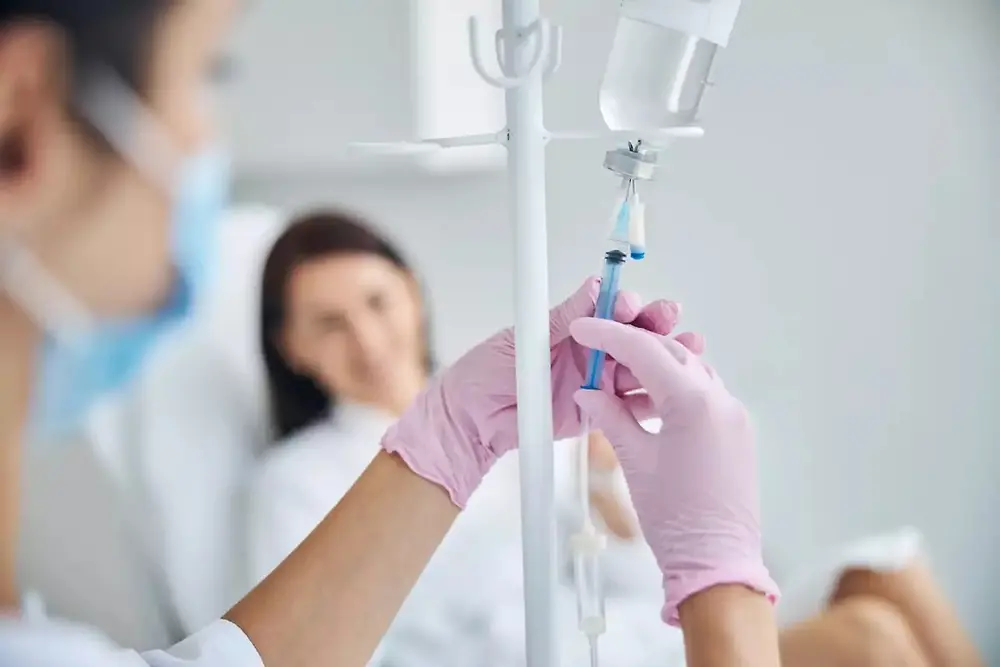 Nahaufnahme von Handschuhen, die in einer klinischen Umgebung eine Spritze vorbereiten.