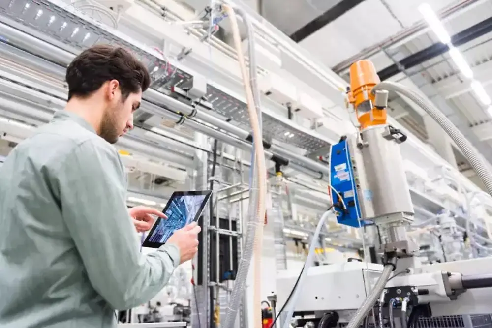 Person überwacht automatisierte Maschinen in einer modernen Produktionsanlage.