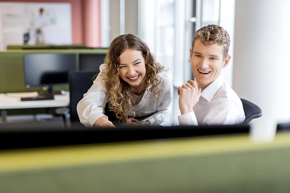 Zwei junge Berufseinsteiger:innen arbeiten gemeinsam an einem Schreibtisch in einem modernen Büroumfeld – stellvertretend für Jobs für Studierende und Einstiegspositionen.