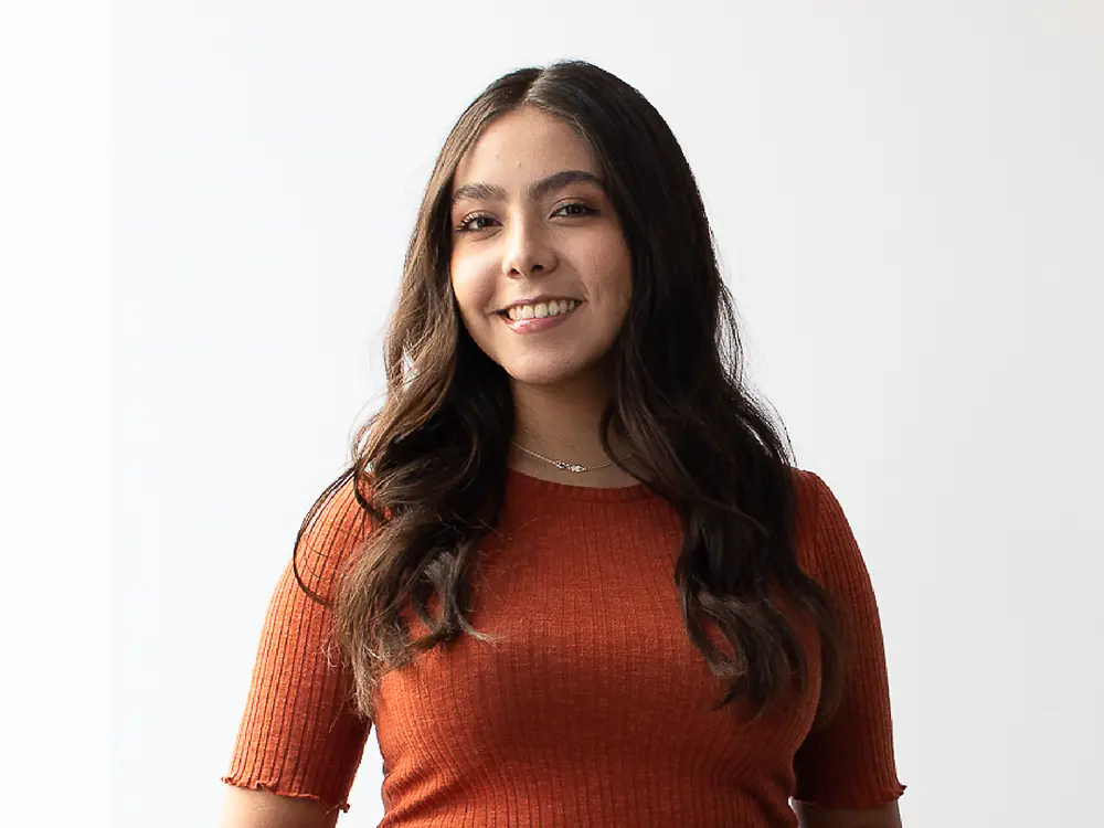 Eine Talent Acquisition Managerin aus Mexiko trägt ein orangefarbenes geripptes Kurzarmtop und gibt Tipps, wie man auf LinkedIn auffällt.