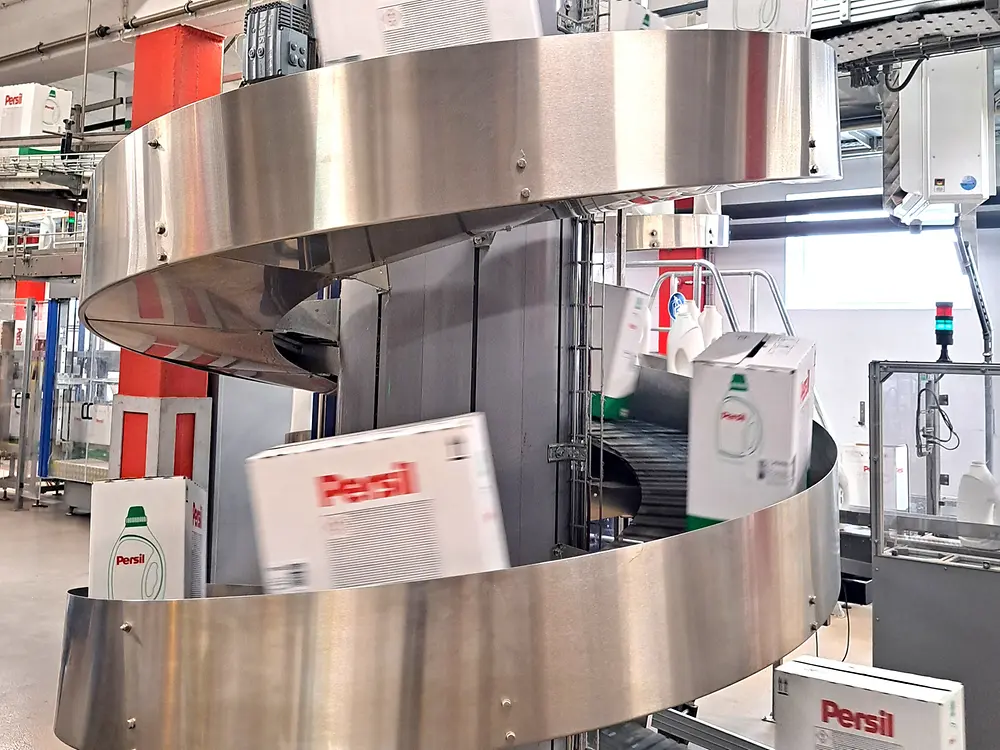 Nahaufnahme eines kreisförmigen Fördersystems mit Persil-Kartons in der Produktion.