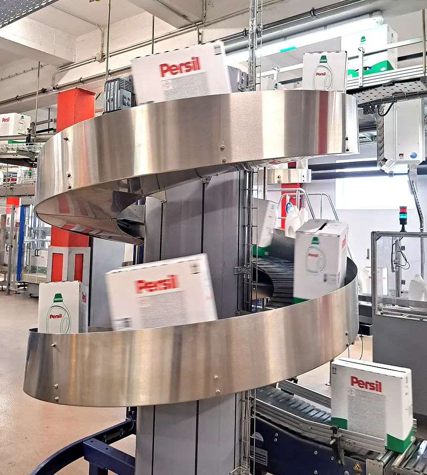 Nahaufnahme eines kreisförmigen Fördersystems mit Persil-Kartons in der Produktion.