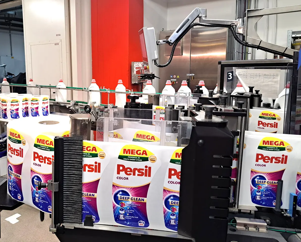 Mehrere Persil-Waschmittelflaschen am Ende der Produktionslinie auf einem Förderband gruppiert.