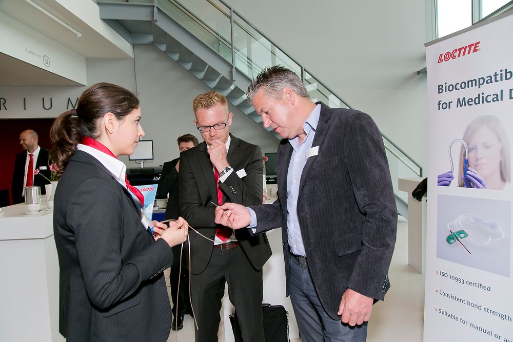 

Henkel experts Lucie Heidar and Maarten Adolfs explain the applications of biocompatible adhesives for medical devices to a customer (right).