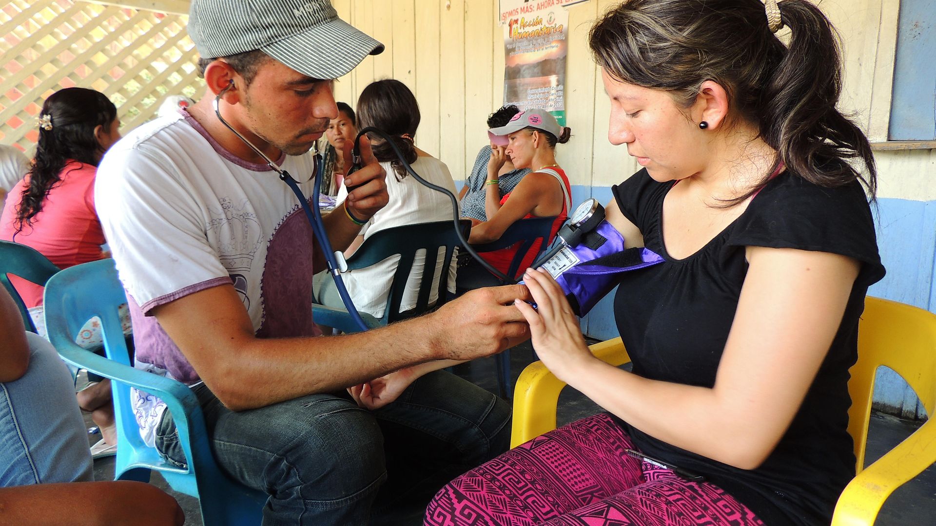 With the help of a medical student (right), a member of the Valle del Río Cimitarra community learns how to measure blood pressure.