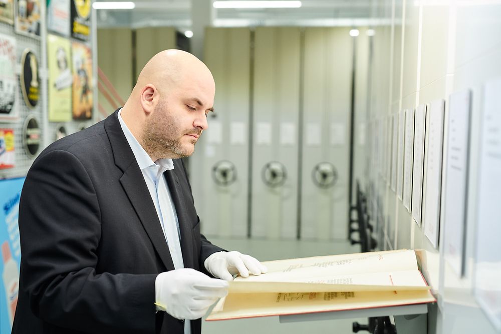 Der Geschichte von Henkel auf der Spur: Archivar Benjamin Obermüller blättert durch ein altes Schriftdokument.